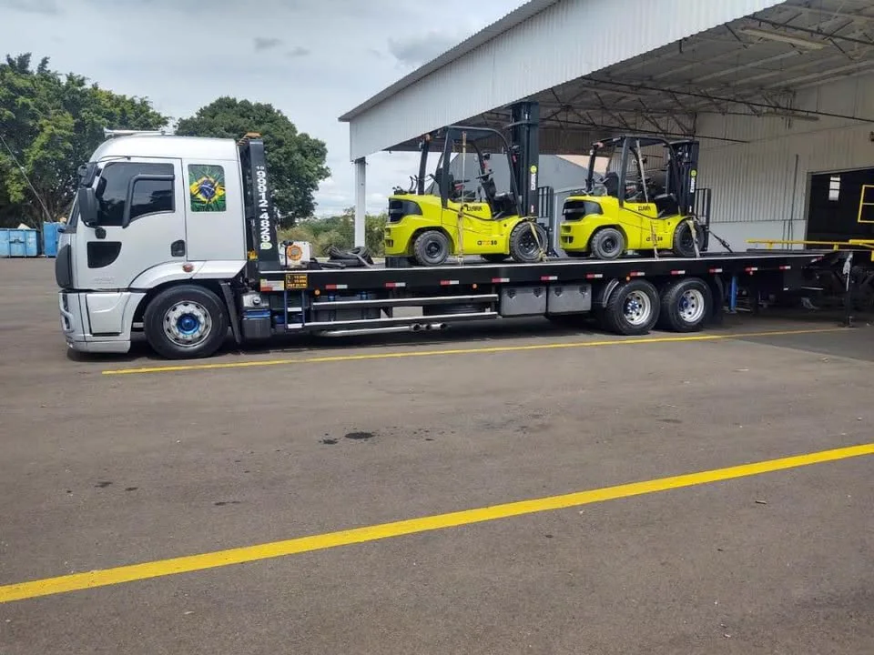 Caminhão transportando empilhadeiras em operação industrial