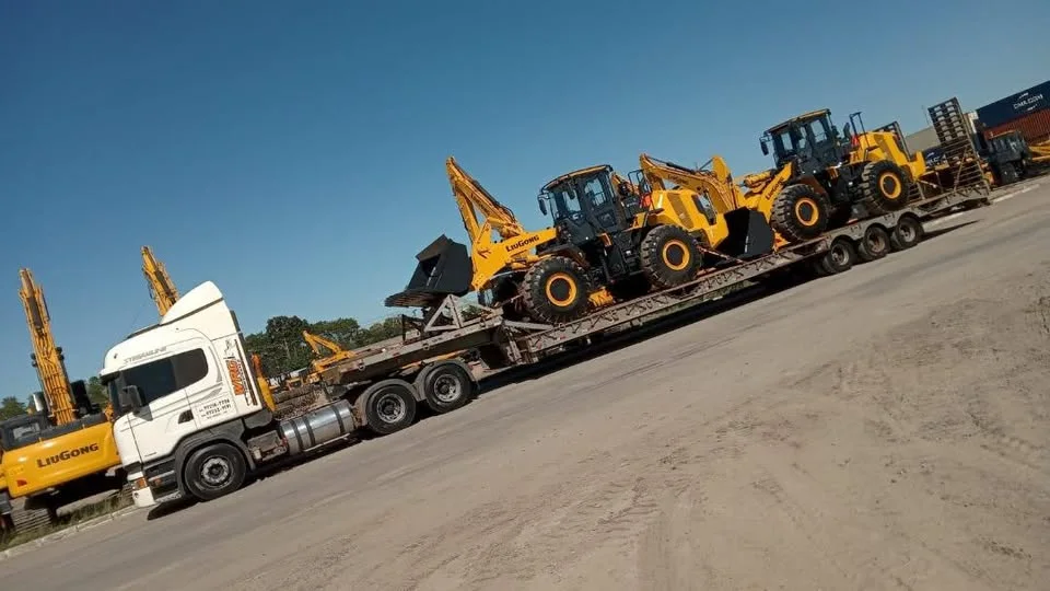 Caminhão prancha transportando equipamentos amarelos Liugong